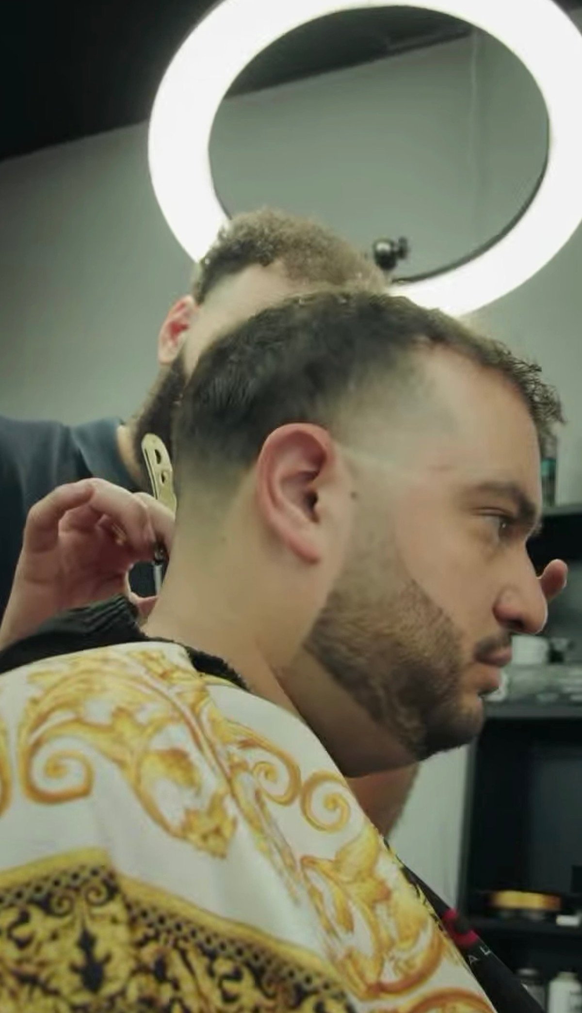 Barber at work with ring light, fresh fade and beard detail